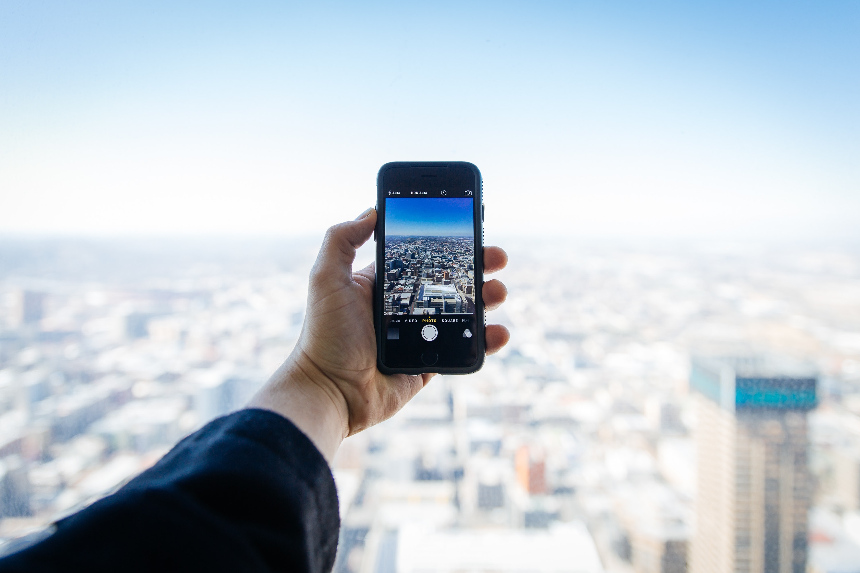 Hand holding iPhone taking picture of a city